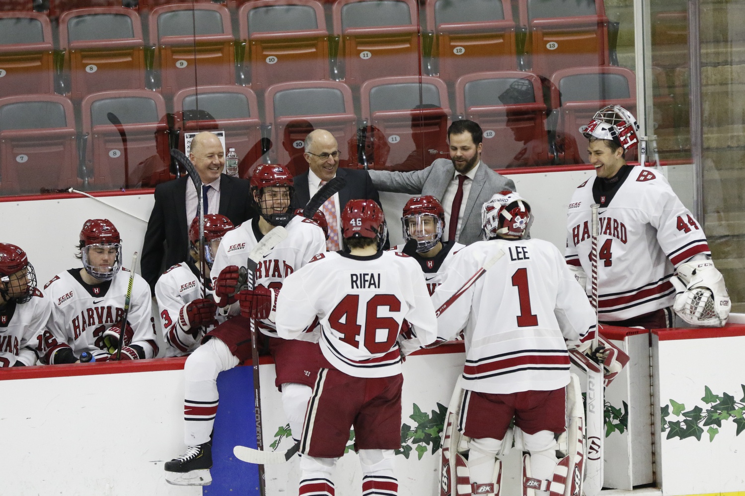Harvard head coach Ted Donato (left) shares a light moment with his team and fellow coaches during a timeout against St. Lawrence on March 7, 2020.