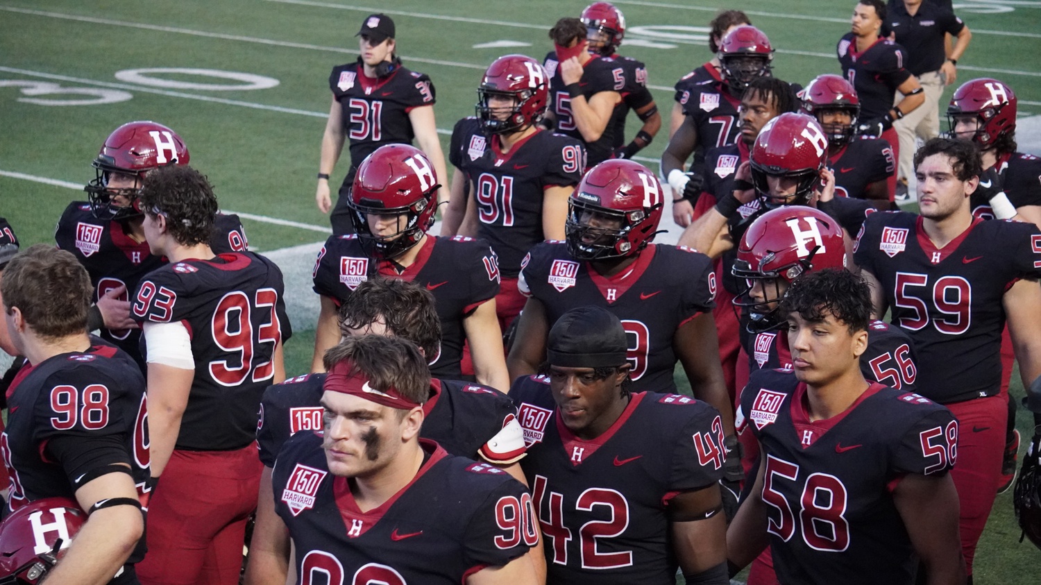 Harvard defensive line gathers on the sideline in its game against Dartmouth last Saturday. For the first time since 2021, the defense didn't allow a single touchdown for the entire game.