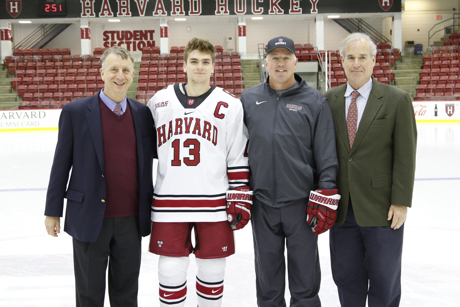 Harvard head coach Ted Donato (second from right), Faculty Fellow William Alford (left), and Faculty Fellow Tim Brown (right) pose with Nathan Krusko, the team's captain in 2019-2020, at the squad's media day in October 2019.